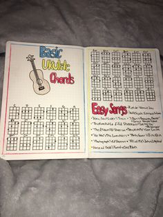 an open book with music worksheets and guitar chords on the pages, sitting on a bed