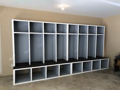 a room filled with lots of white shelves next to a black chair and a window