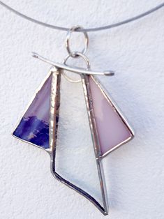 a silver necklace with purple and white glass pieces hanging from it's center piece