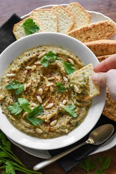 a white bowl filled with hummus and garnished with parsley