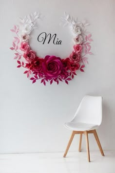 a white chair sitting in front of a wall with pink flowers and the word ma on it