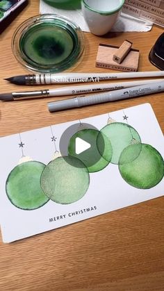 a christmas card with green ornaments on it and some crayons next to it