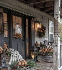 the porch is decorated with pumpkins, pine cones and other fall decorations on it