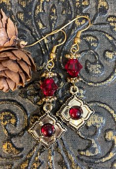 These lovely romantic red and gold vintage-style earrings are perfect for the holidays or anytime. Indie gold flower charms with red glass centers hang below bicone ruby red Swarovski crystals (which are almost impossible to find anymore). Earrings hang 2 inches from gold French ear hooks. Red And Gold Earrings, Indie Earrings, Black Wedding Gowns, Raven Pendant, Holiday Earrings, Vintage Style Earrings, Holiday Earring, Victorian Christmas, Earrings Red