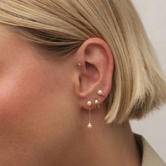 a close up of a person wearing earring with pearls on the outside of their ears