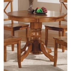 a wooden table with four chairs and a bowl of fruit on top of the table