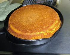 a round cake sitting on top of a black pan next to a frying pan