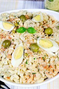 a bowl filled with macaroni salad topped with hard boiled eggs and green olives