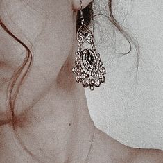 a close up of a woman's face with earrings on her ear and the back of her head