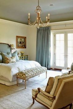 a bedroom with a large bed, chandelier and two chairs in front of it