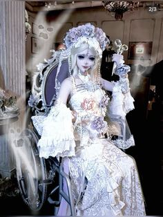 a woman dressed in white is sitting on a chair with an elaborate dress and headpiece