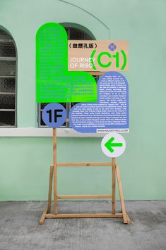 a green sign sitting on top of a wooden stand in front of a blue building