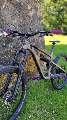 a bike leaning against a rock in the grass