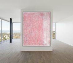 a large pink painting is in the middle of a room with wooden floors and windows