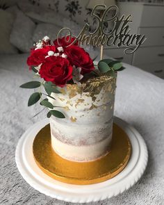 a white and gold cake with red flowers on top