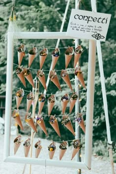 an ice cream display with cones and candies hanging from it's poles in front of trees