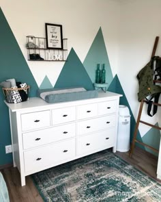 a baby crib with mountains painted on the wall behind it and a rug in front of it