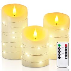 three lit candles sitting next to each other with remotes on the table in front of them