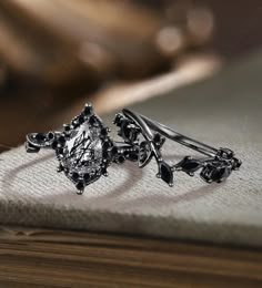 a pair of black diamond earrings sitting on top of a wooden table next to a book