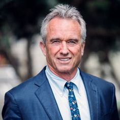 a man in a suit and tie smiling at the camera