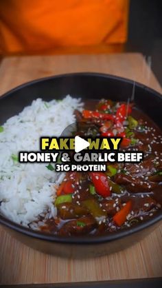 a pan filled with rice and meat on top of a wooden table next to a person