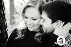 black and white photograph of a couple embracing each other in front of a tree trunk