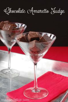 two martini glasses filled with chocolate on top of a red table cloth and silver tray