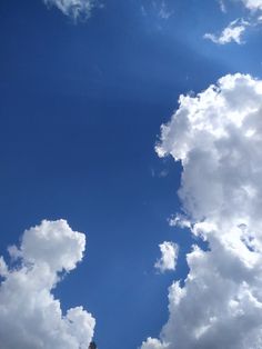 an airplane flying in the blue sky with white clouds