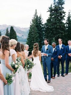 a group of people standing next to each other in front of trees and mountains on a cloudy day