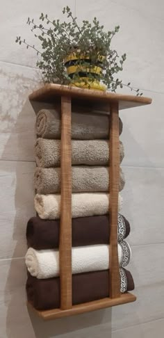 a wooden shelf filled with lots of folded towels and a potted plant on top