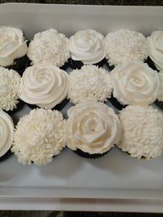 cupcakes with white frosting are arranged in a square box on the table