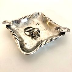 two wedding rings are placed on top of a silver tray that is shaped like an oyster