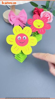 a hand is pointing at some paper flowers