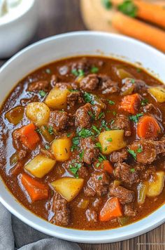 a white bowl filled with beef stew and carrots