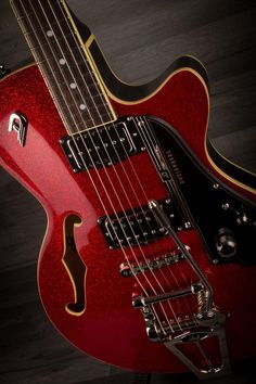 a red electric guitar sitting on top of a wooden floor