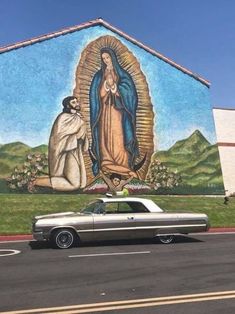 a car parked in front of a building with a mural on it