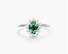 18K White Gold Oval Halo Emerald and Diamond Ring (7.0x5.0mm). Celebrate a classic look with this stunning ring featuring an oval emerald surrounded by a halo of glistening diamonds. The unique prong setting of the diamond halo lends a vintage feel to this chic piece that will instantly upgrade any look. Elegant Oval Cabochon Emerald Ring With Halo Setting, Elegant Emerald Ring With Oval Cabochon Halo Setting, Formal Oval Emerald Ring With Halo, Classic Oval Emerald Halo Ring, Elegant Green Oval Halo Ring, Oval Halo Ring With May Birthstone, Elegant Oval Halo Ring For May Birthstone, Emerald Silver Ring, Emerald And Diamond Ring