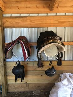 hats and boots are hanging on the wall next to each other in a barn stall