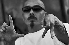 a man with two fingers in the air and one hand pointing to the side while wearing sunglasses