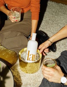 two women are sitting on the floor and one is holding a wine glass in her hand