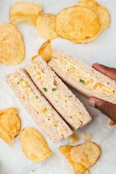 a person holding a sandwich with chips on the side