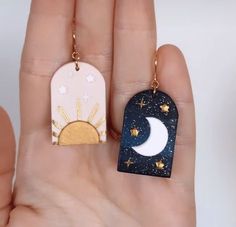 two small tags with stars and the moon on them are being held in someone's hand