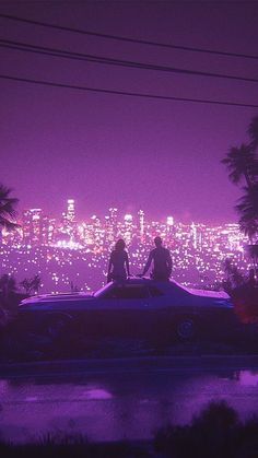 two people sitting on top of a car in front of a city skyline at night