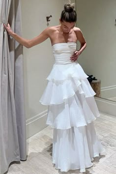 a woman in a white dress standing next to a curtain