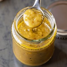 a spoon full of mustard sitting on top of a jar