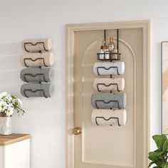 three towel racks are hanging on the wall in front of a white door with a potted plant next to it