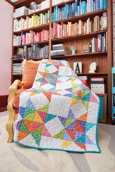 a colorful quilt on a chair in front of a bookshelf full of books