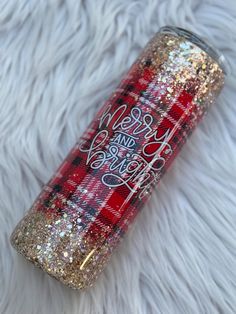 a red and gold flannel glitter tumble with the words merry and happy on it