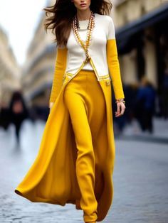 a woman walking down the street wearing yellow pants and a white top with long sleeves