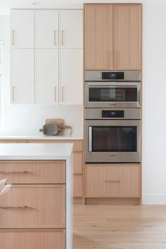 a kitchen with two ovens and an island in the middle of it, next to white cabinets